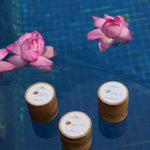 The three NB face packs arranged on glass above still water with lotus blooms