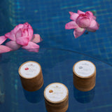 The three NB face packs arranged on glass above still water with lotus blooms