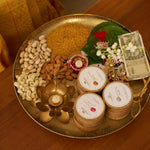 The three NB face packs set into a brass festive thali with dry fruits, a diya and rakhi threads