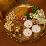 The three NB face packs set into a brass festive thali with dry fruits, a diya and rakhi threads