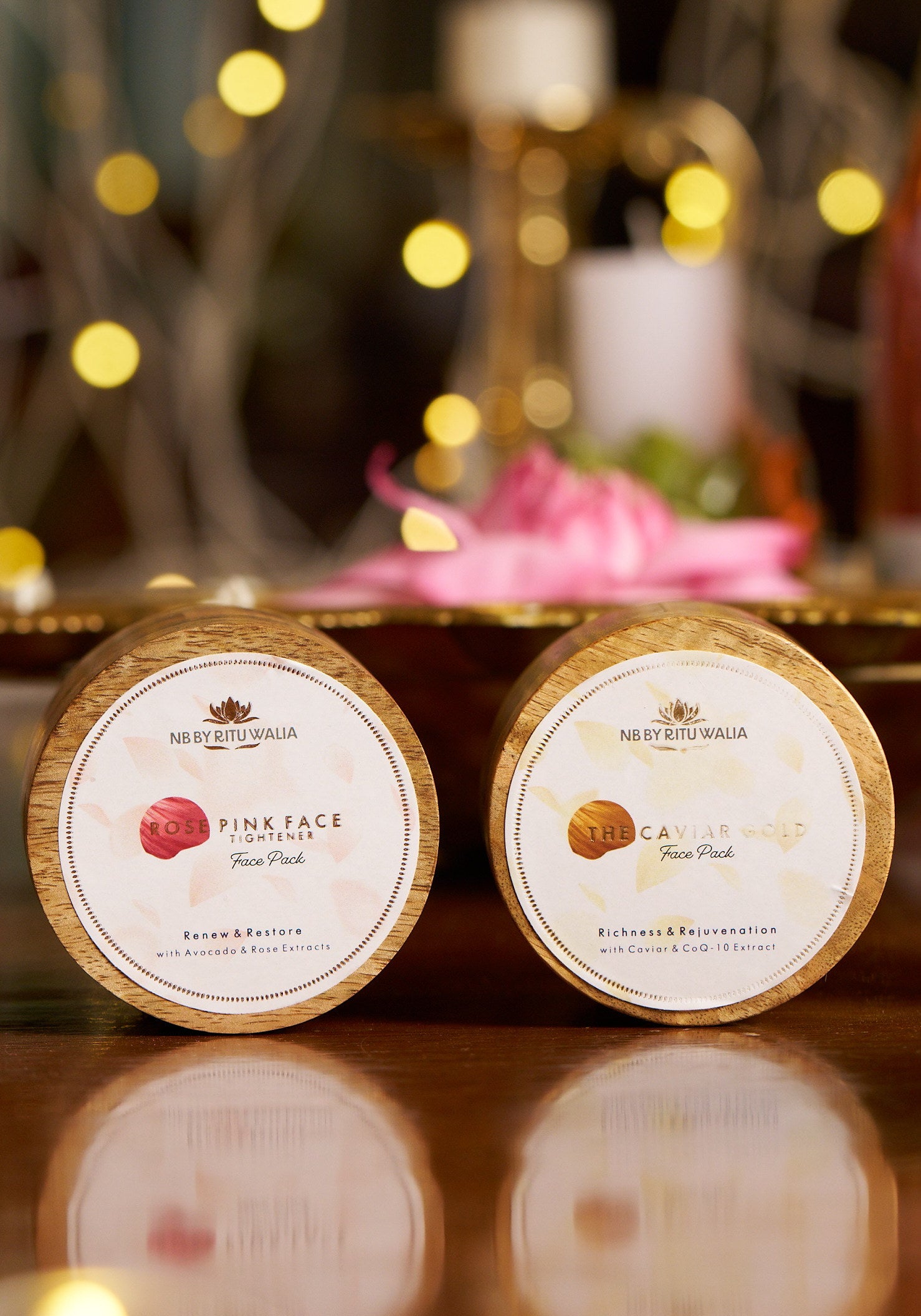 Engraved lids of the Rose Pink Face Tightener and The Caviar Gold Face Pack against warm candlelight
